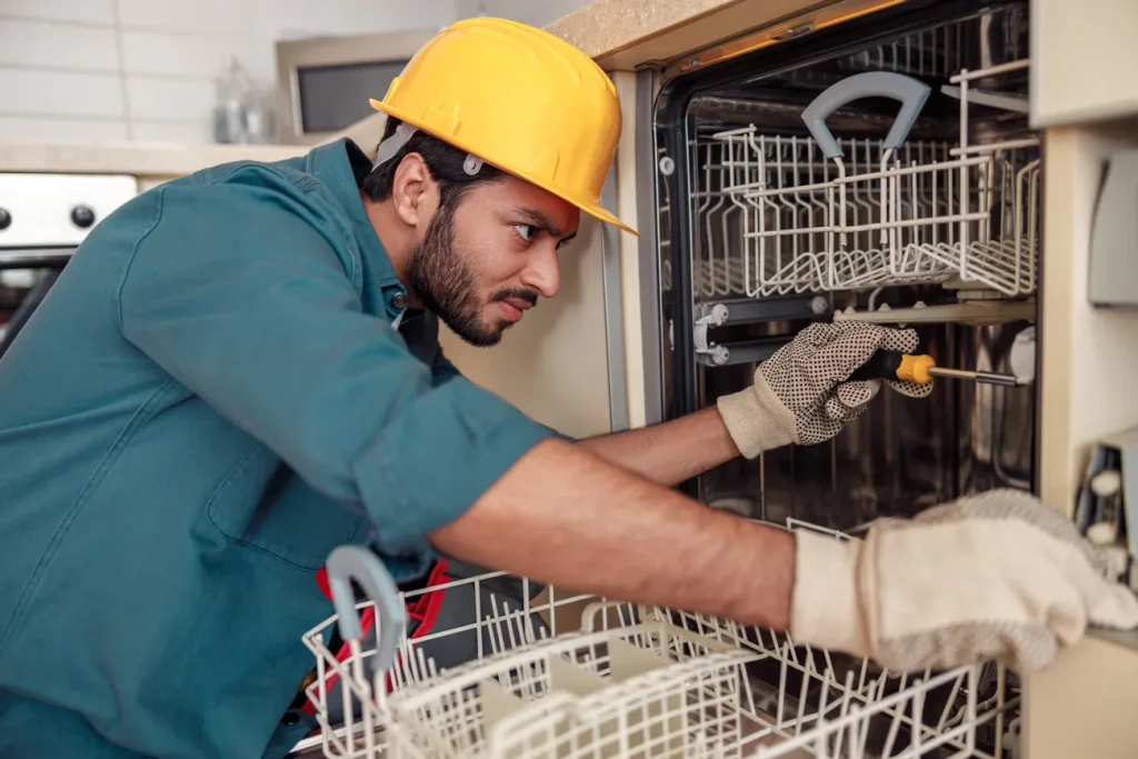 آشنایی technician در حال انجام تعمیرات در ماشین ظرفشویی روی قفسهها